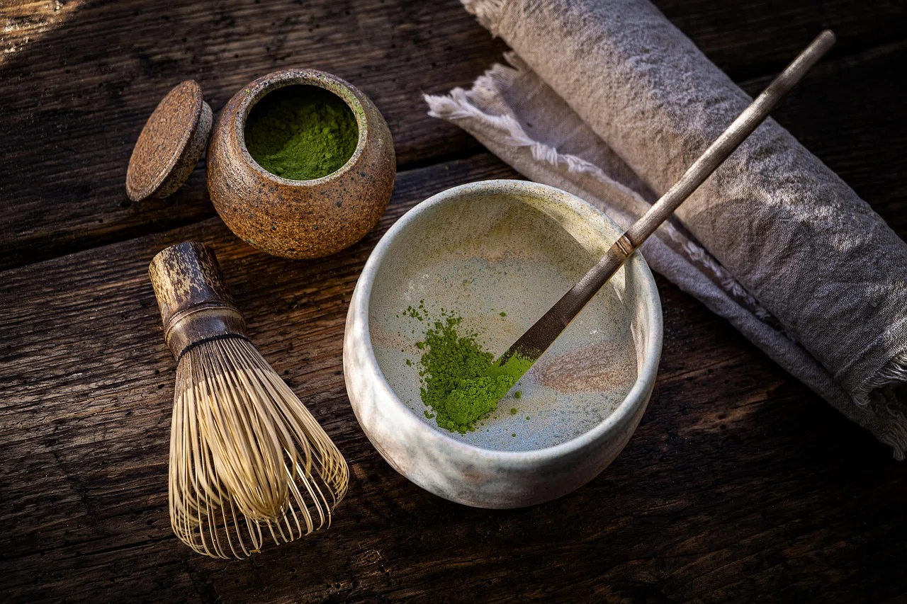 Macro shot of vivid green ceremonial matcha powder being poured from a single-serve sachet into a bowl